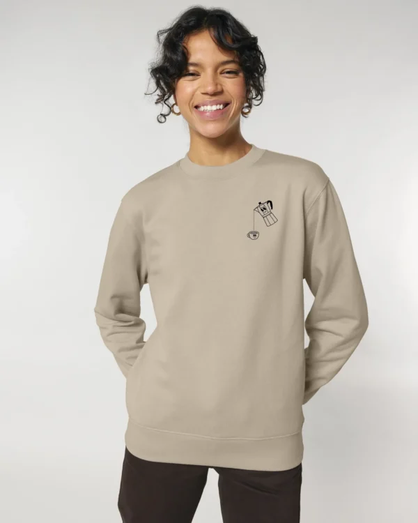 Mujer sonriente con sudadera beige y diseño divertido, luciendo estilo casual y moderno.