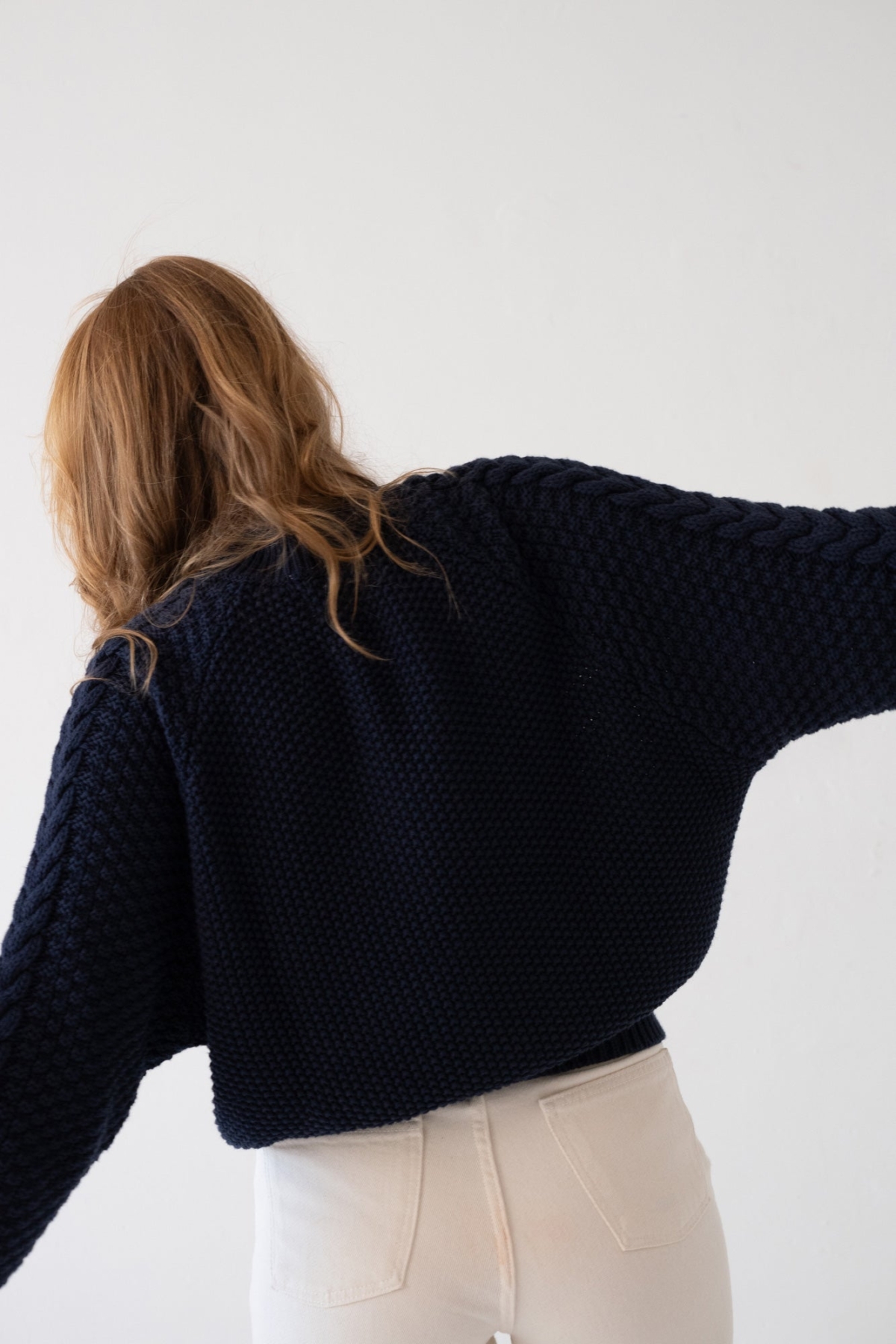 Mujer con suéter de punto azul marino y jeans claros en estilo casual y relajado.