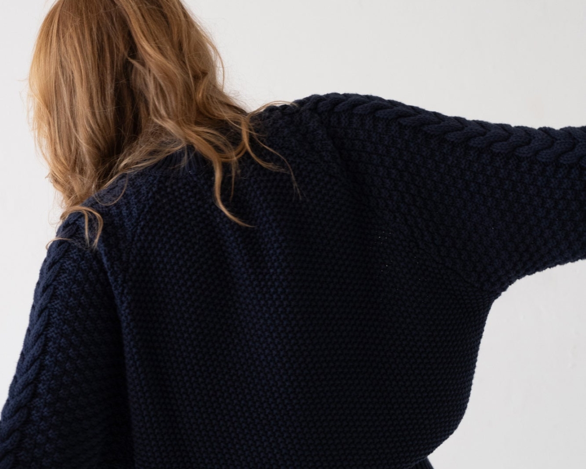 Mujer con suéter de punto azul marino y jeans claros en estilo casual y relajado.