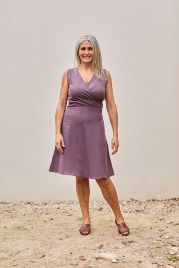 Mujer segura con vestido lavanda, posando elegantemente en un entorno natural y relajante.