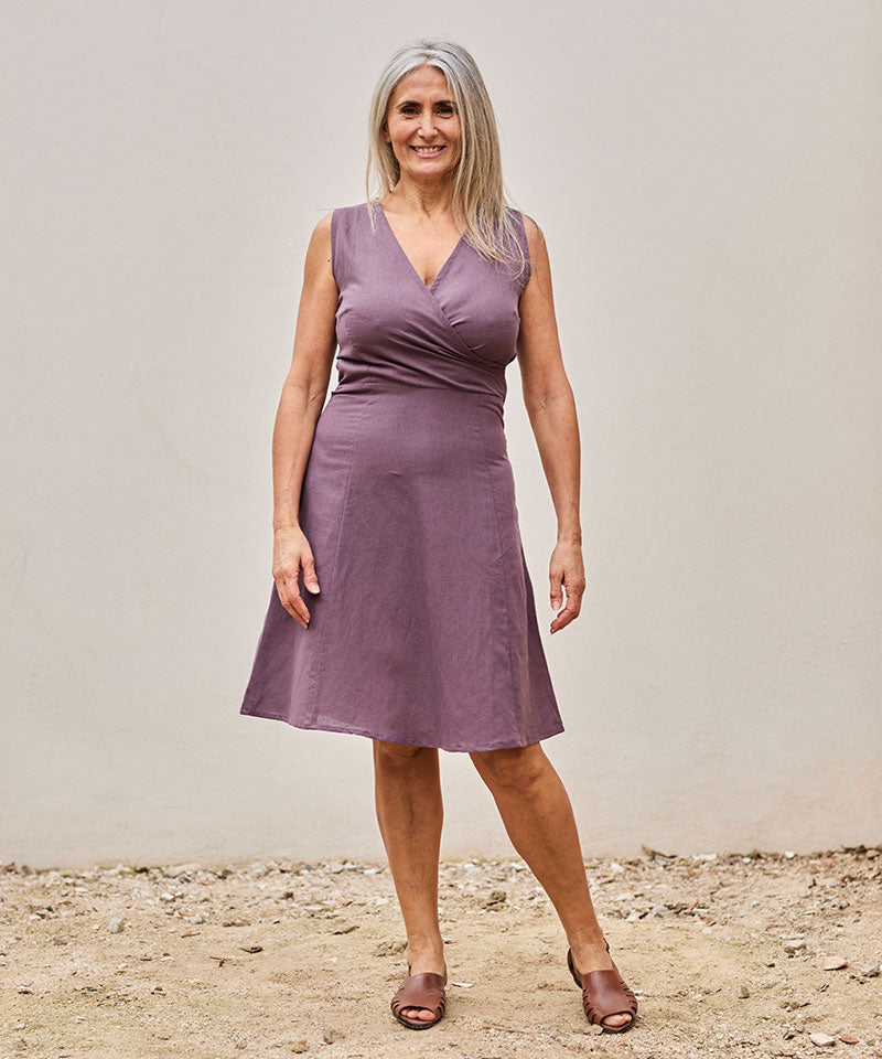 Mujer segura con vestido lavanda, posando elegantemente en un entorno natural y relajante.