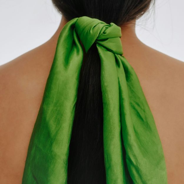 Coletero vibrante en verde lima que combina elegancia y estilo con cabello largo y oscuro.