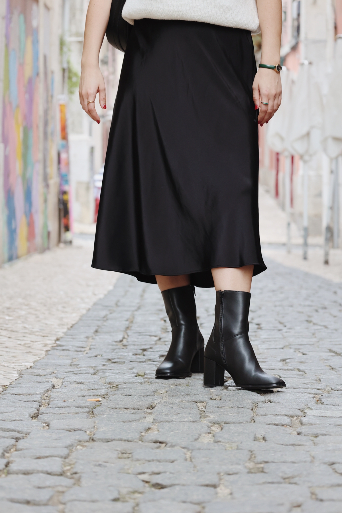 Moda urbana en una calle empedrada con botas elegantes y un falda fluida.