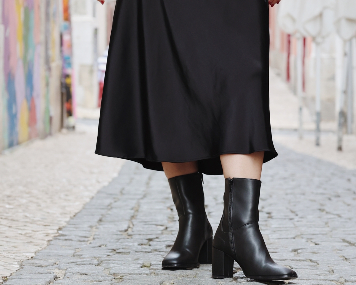 Moda urbana en una calle empedrada con botas elegantes y un falda fluida.