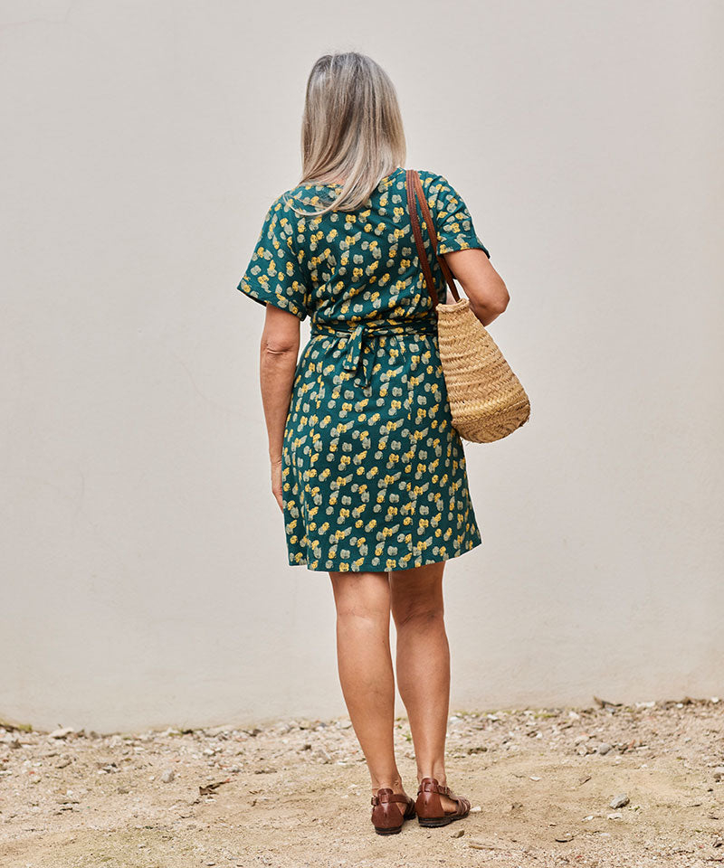 Mujer elegante con vestido verde en un ambiente exterior relajante y cálido.