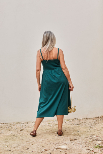 Mujer con vestido teal y ramo de flores secas, transmitiendo serenidad y elegancia.