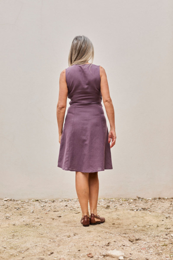 Mujer con vestido lavanda elegante en un fondo minimalista, transmitiendo calma y confianza.