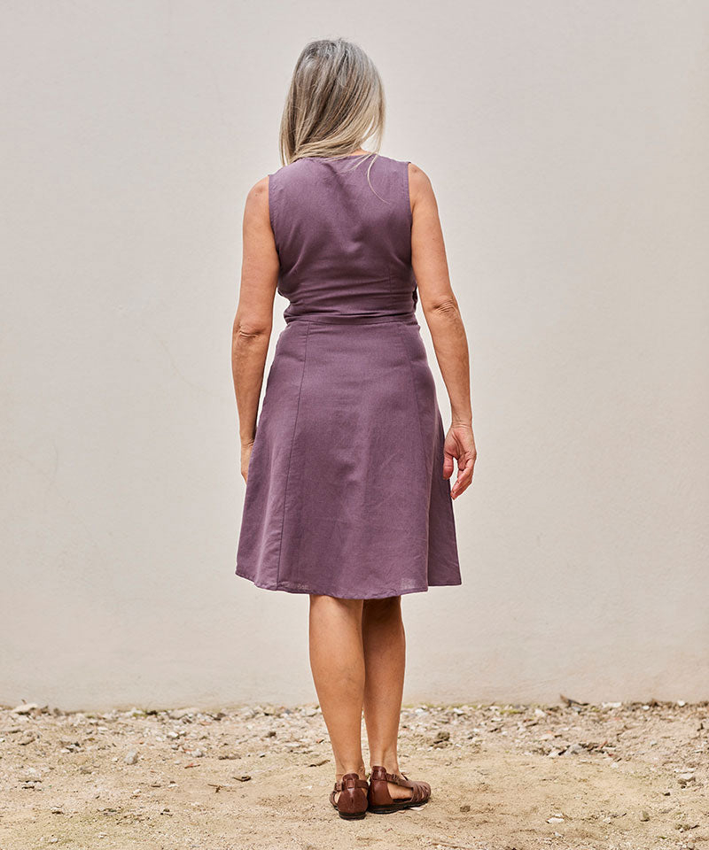 Mujer con vestido lavanda elegante en un fondo minimalista, transmitiendo calma y confianza.