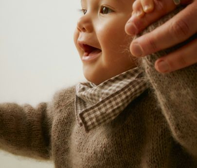 Niño sonriente caminando con apoyo, irradiando alegría y exploración en un ambiente cálido.