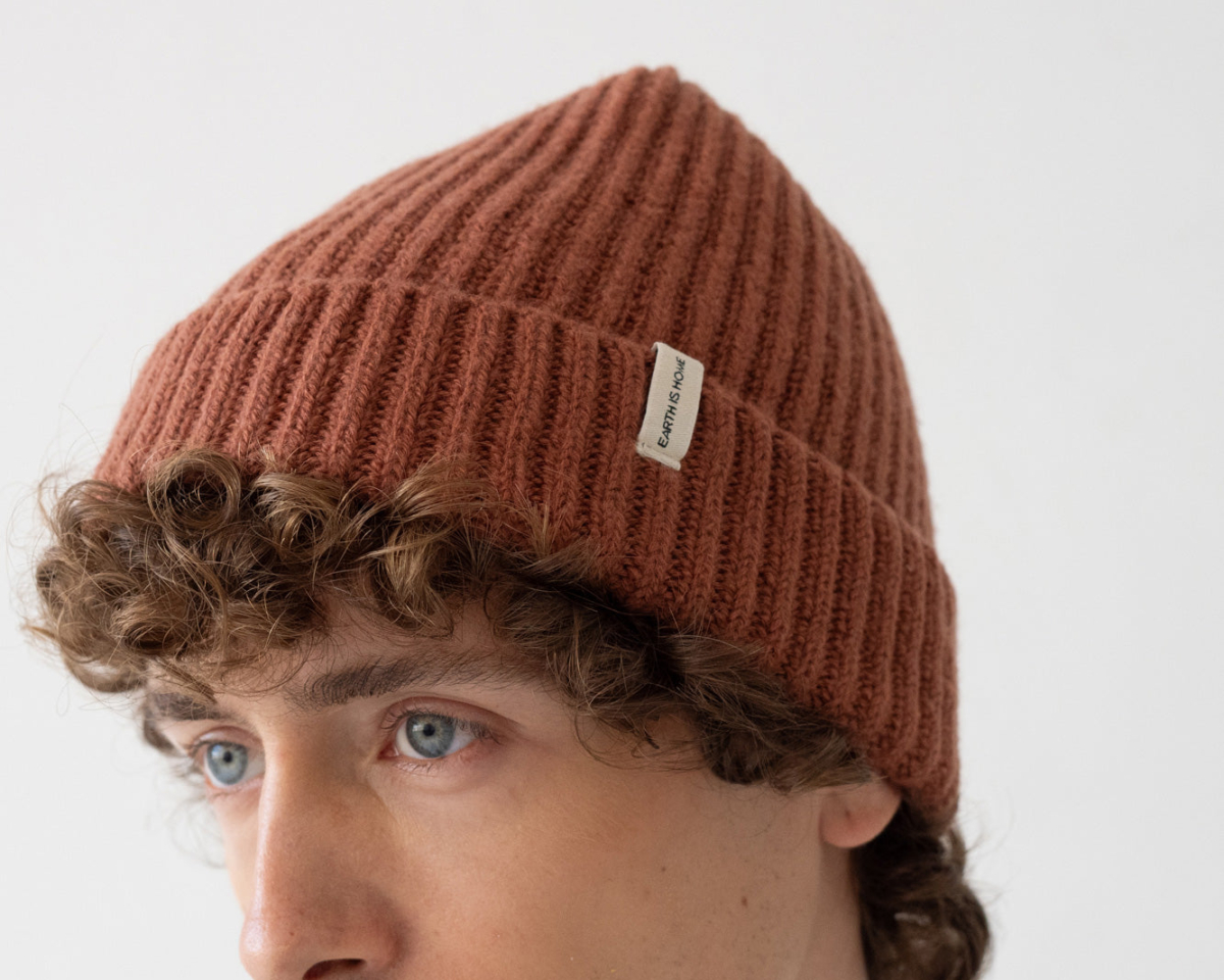 Joven con gorro acogedor, pelo rizado y mirada serena. Estilo casual y sofisticado.