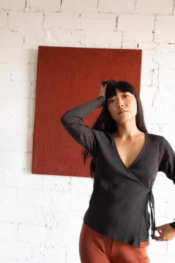 Mujer joven elegante frente a un lienzo rojo en pared blanca, irradiando confianza y estilo.